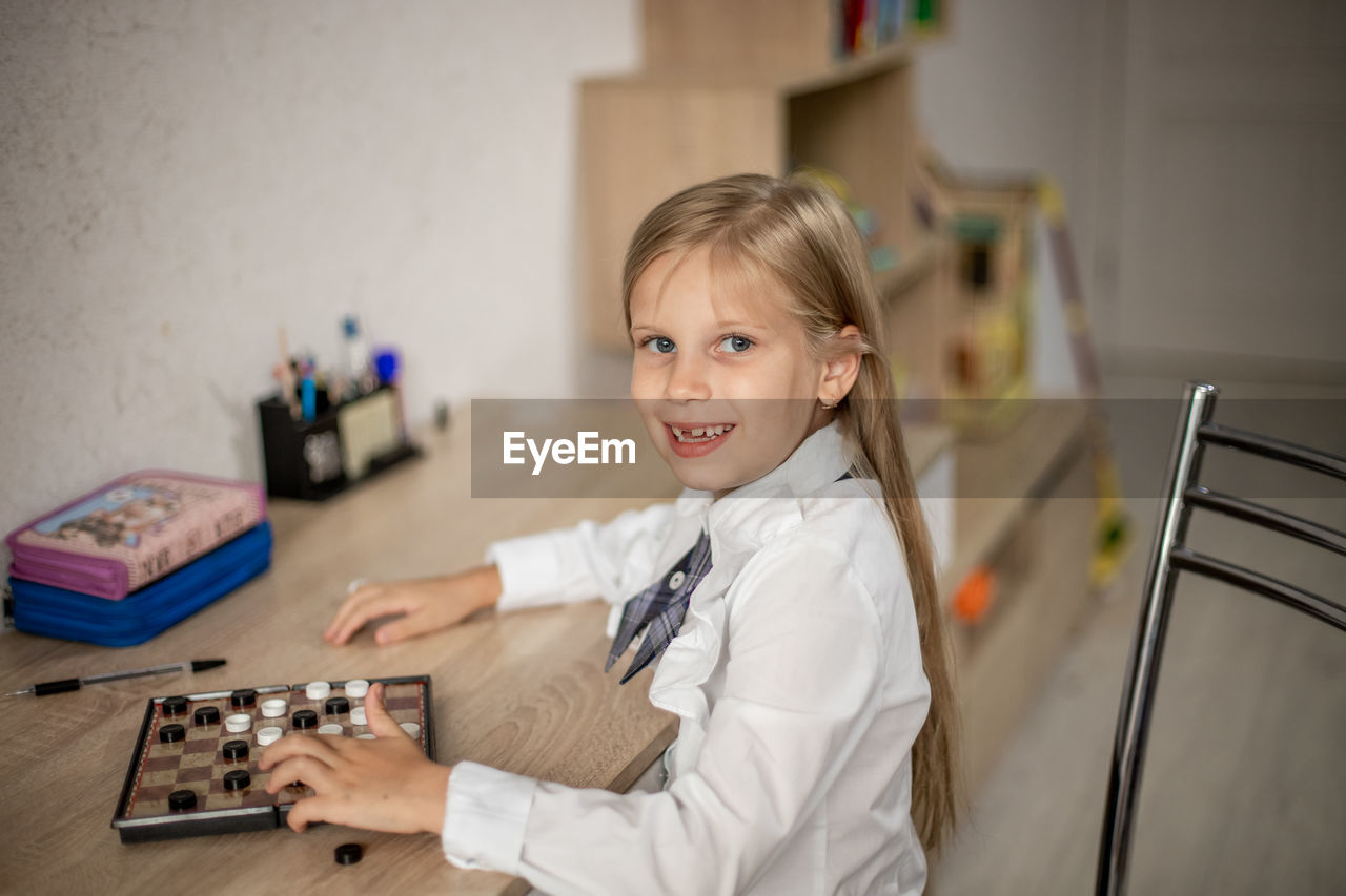 portrait of cute girl playing with toy while standing against wall