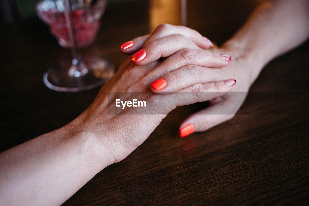 Cropped image of lesbians holding hands on table