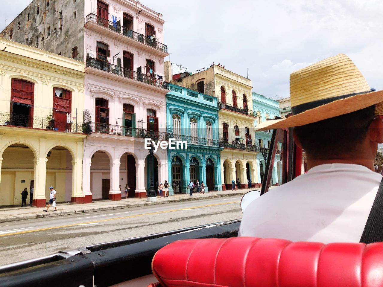 Rear view of man wearing hat while riding convertible car in city