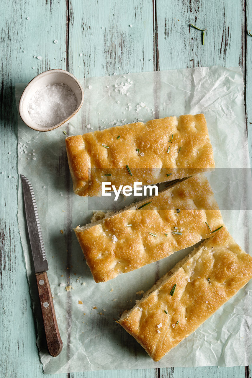 Slice of italian focaccia, on wooden table.