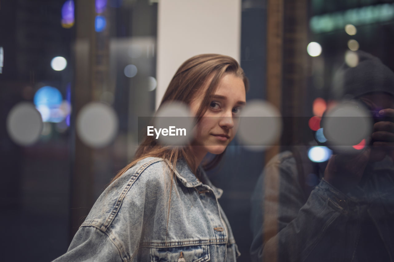 Portrait of young woman seen through glass window