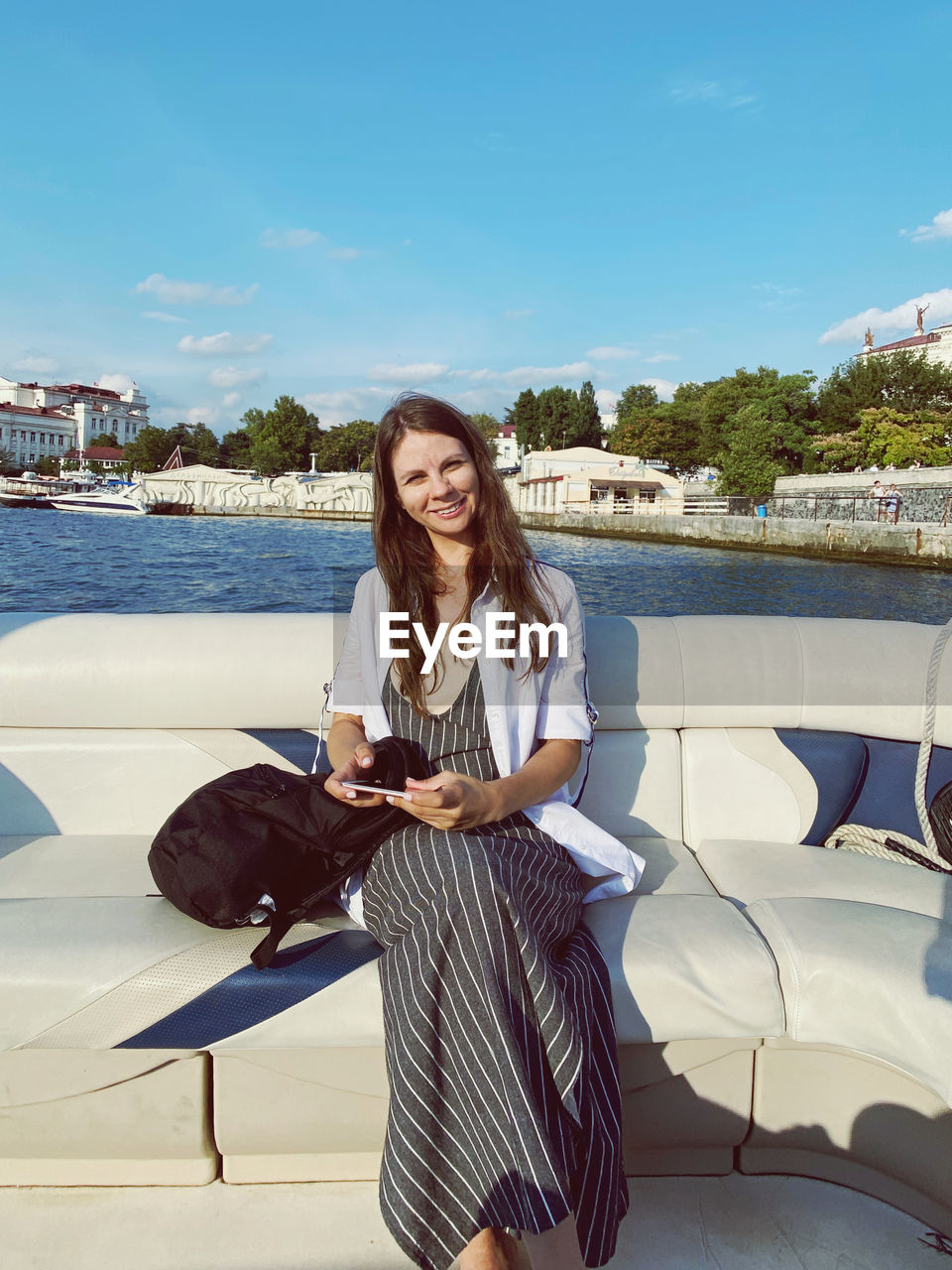 Portrait of young woman standing against lake