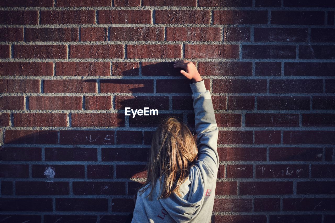 Woman standing against brick wall