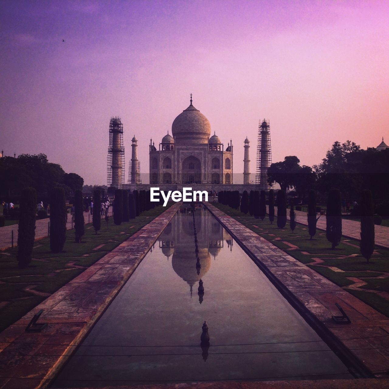 Reflecting pool towards taj mahal against sky during sunset