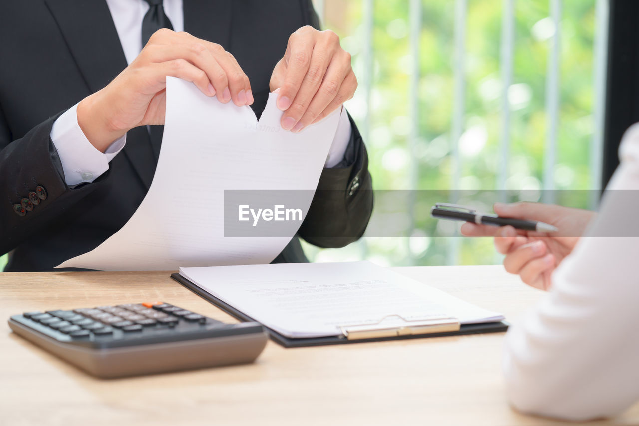 Businessman tearing contract paper while sitting in office