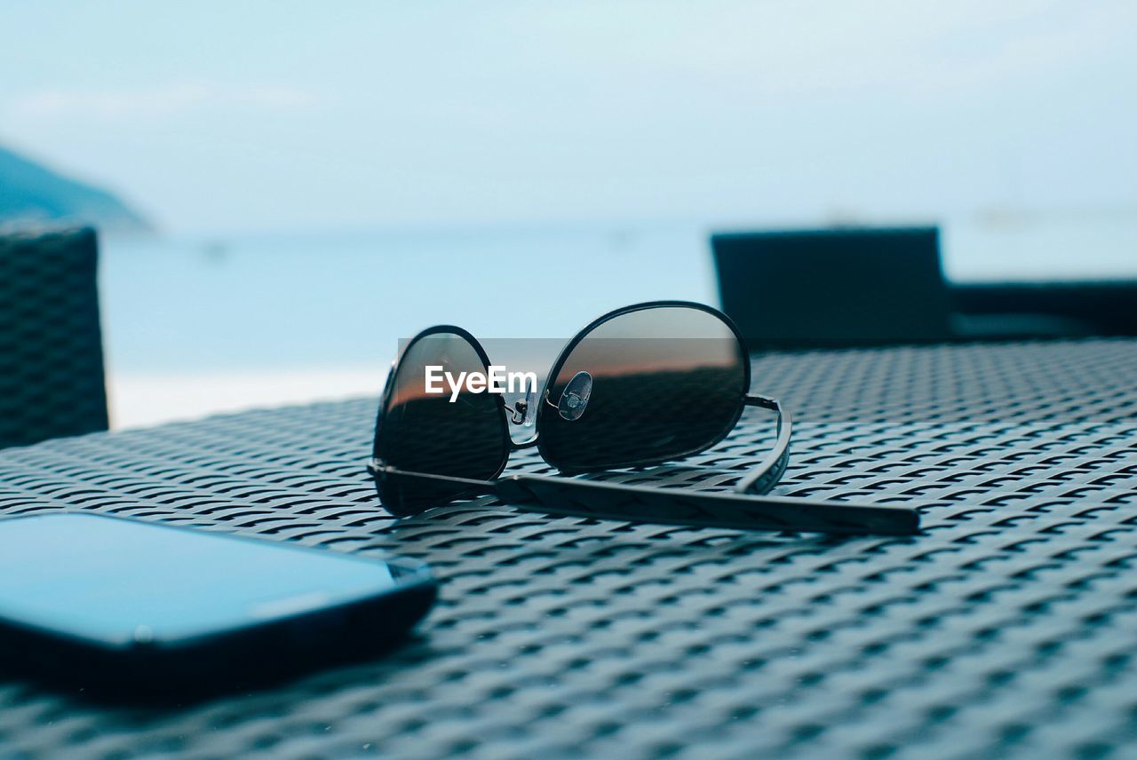 Close-up of sunglasses and smart phone on table