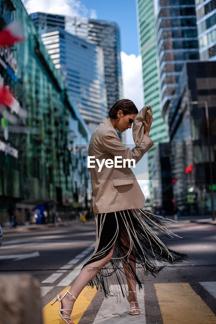 Side view of young woman walking on street in city