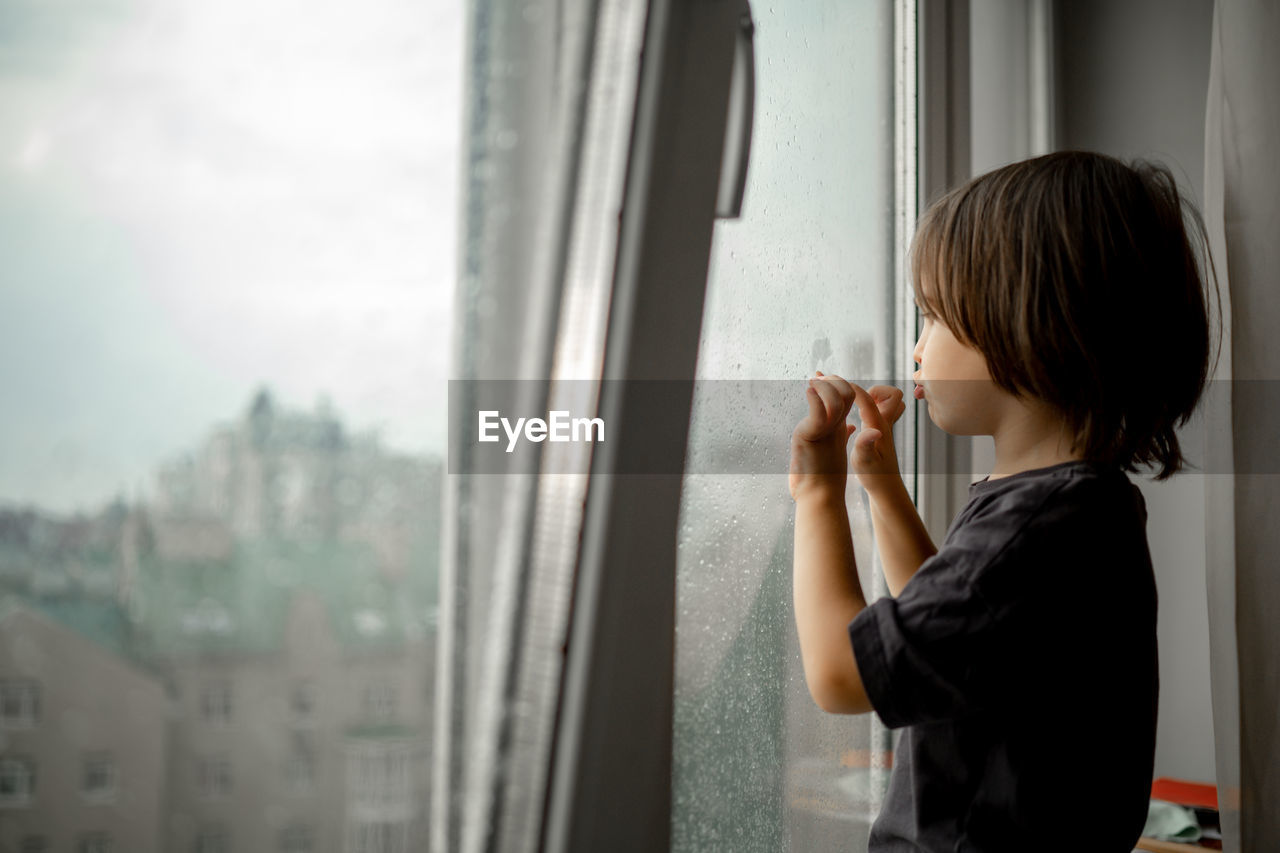 side view of man looking through window