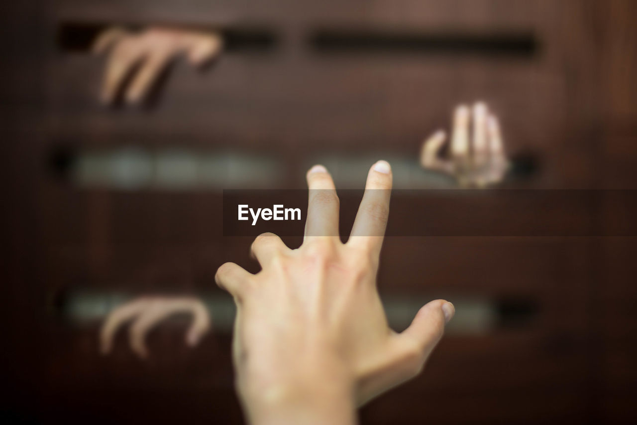 Close-up of human hand gesturing towards cabinet
