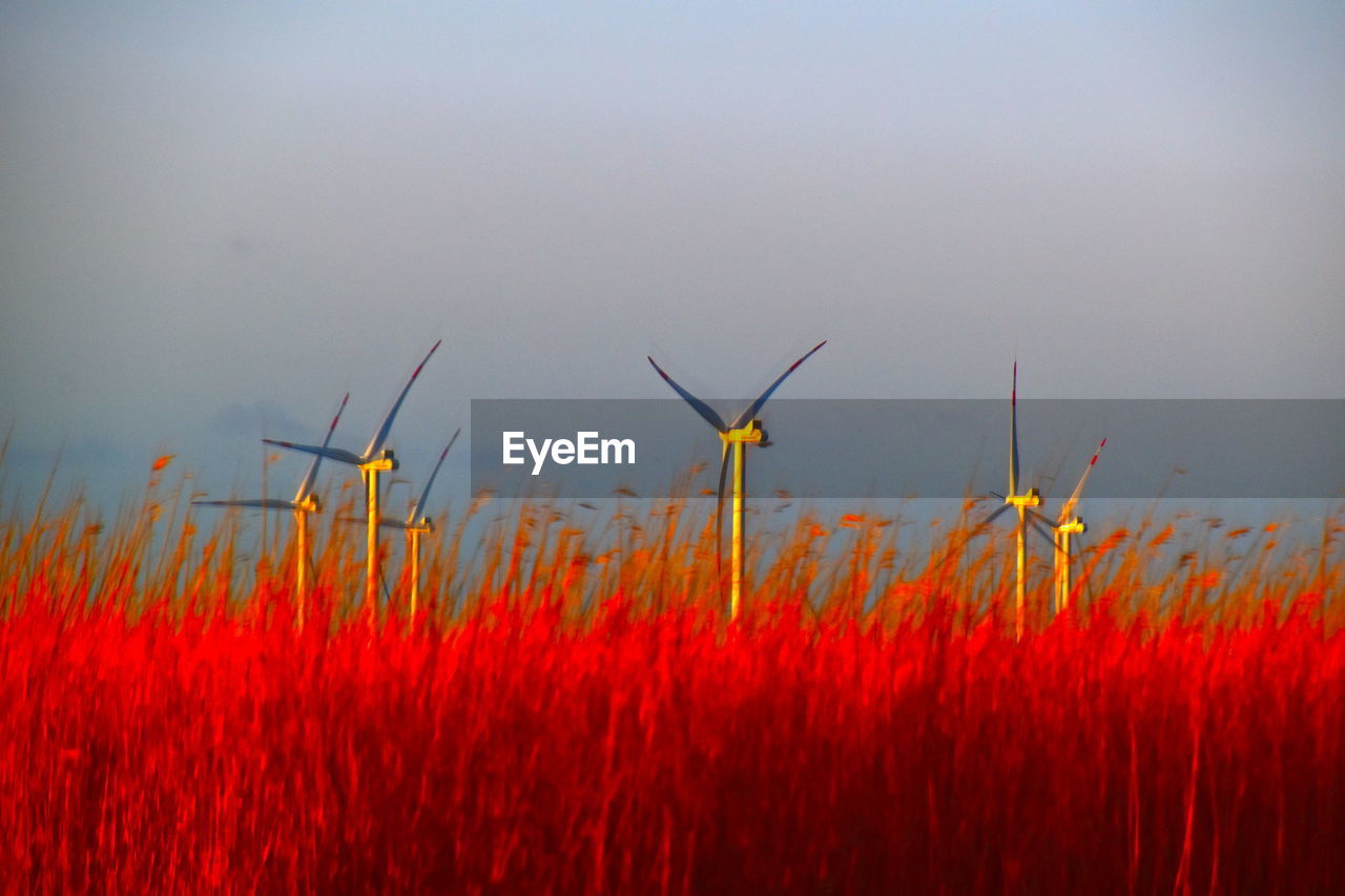 CLOSE-UP OF RED WIND TURBINES ON FIELD