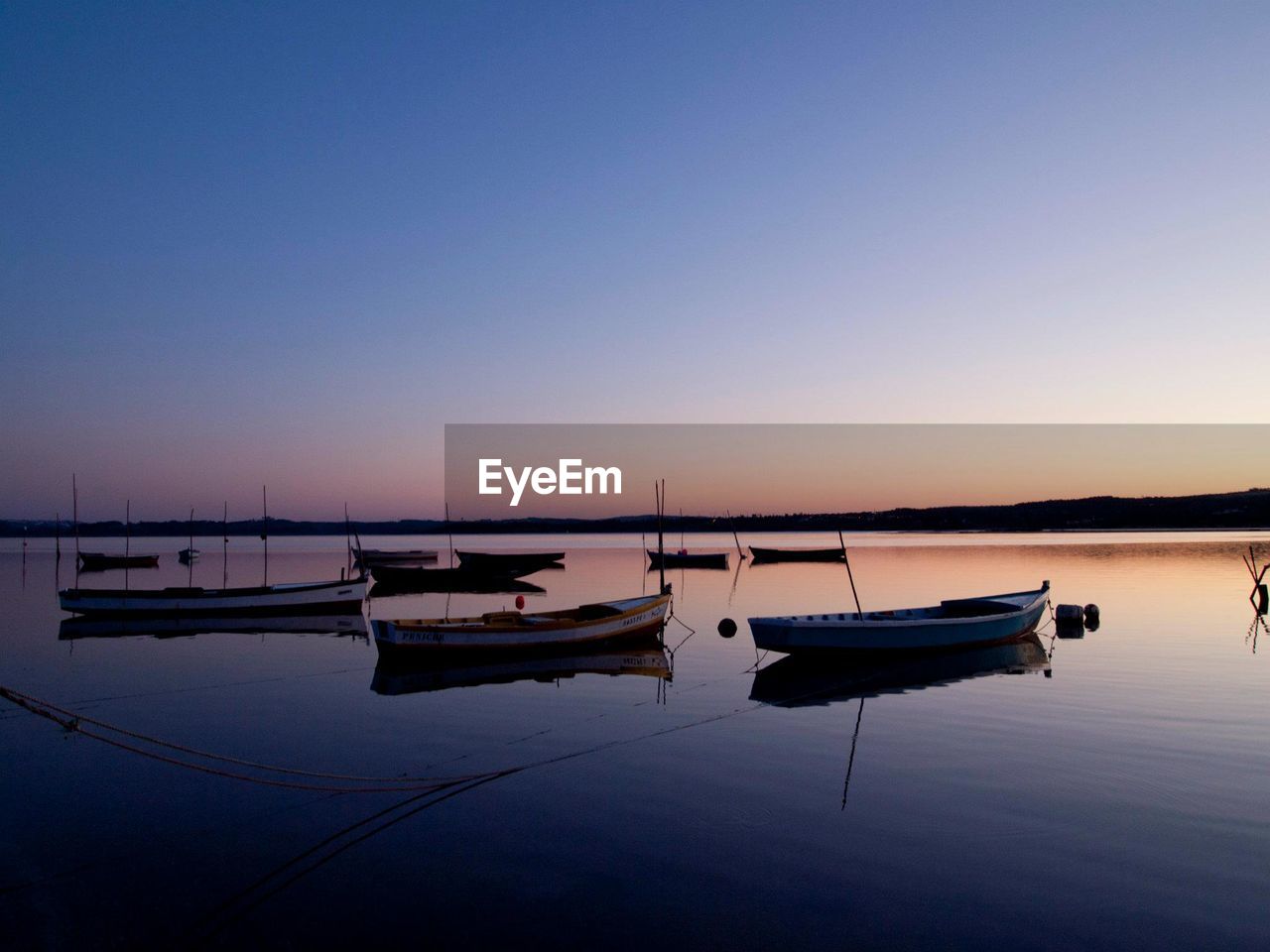 Boats moored in sea against clear sky during sunset