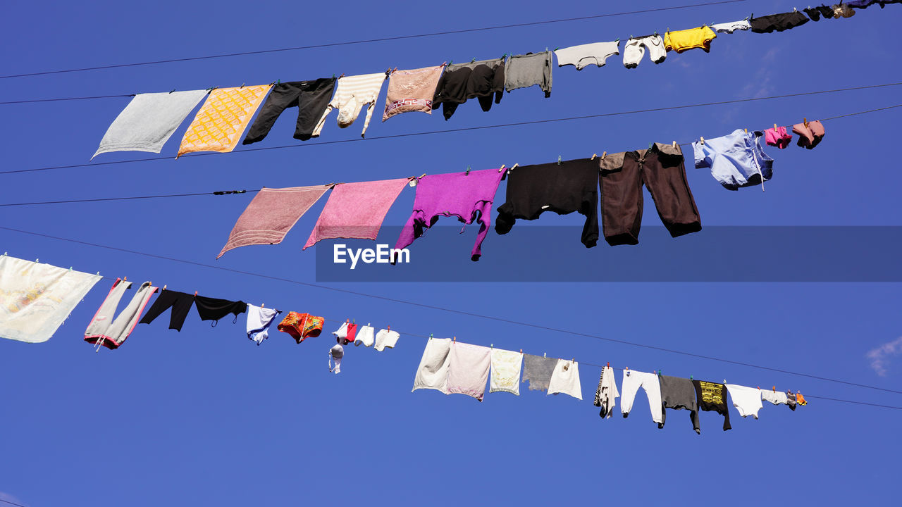 LOW ANGLE VIEW OF CLOTHES DRYING AGAINST SKY