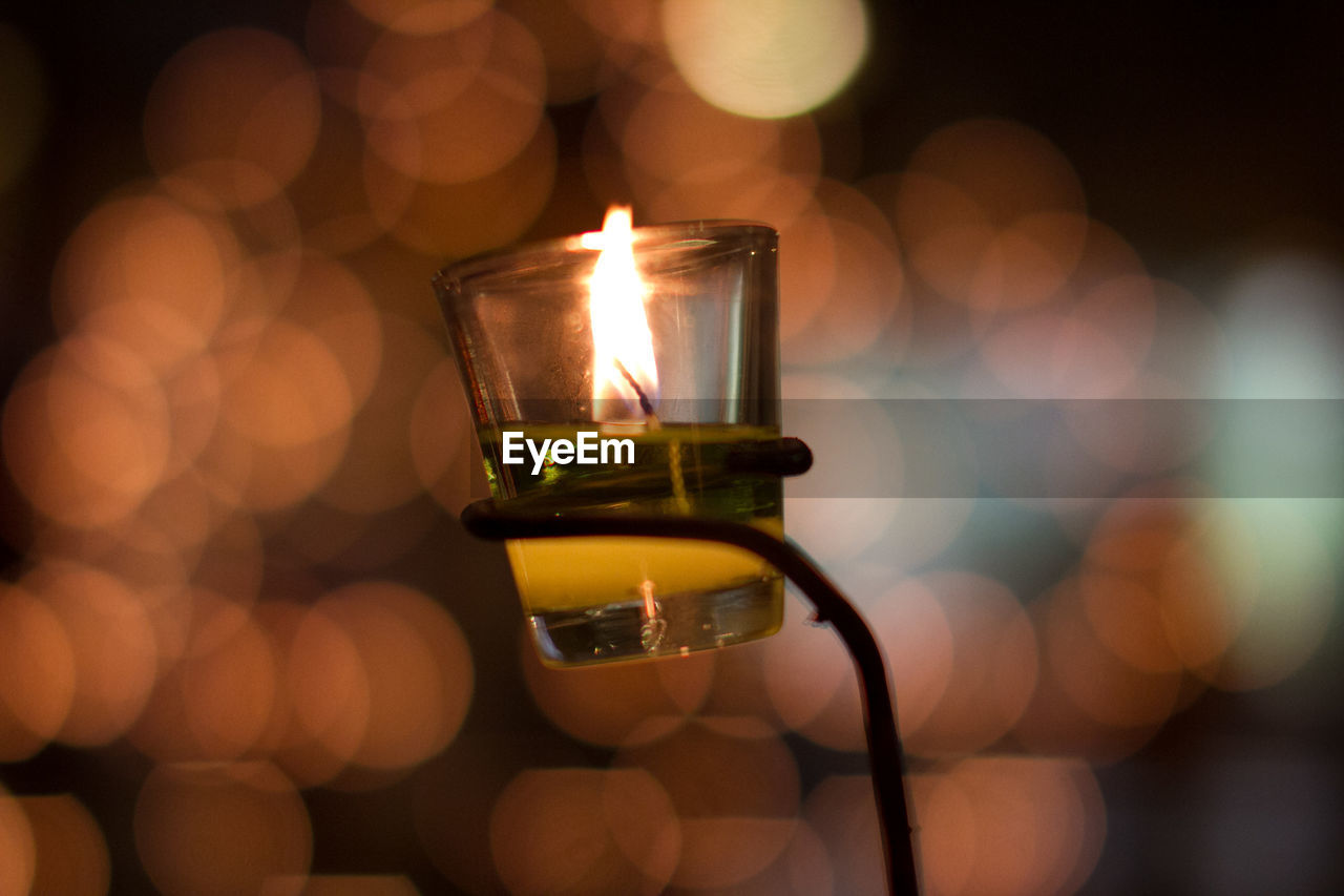 Close-up of illuminated tea light candle against defocused lights