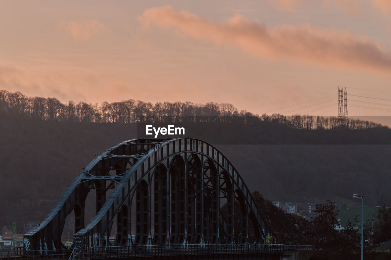 Old iron bridge over river meuse, belgium at dawn