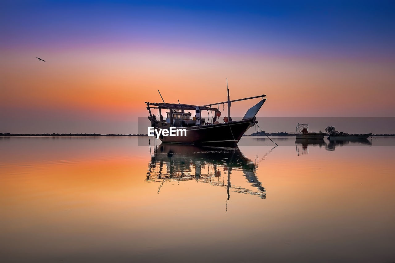 FISHING BOAT MOORED IN SEA DURING SUNSET