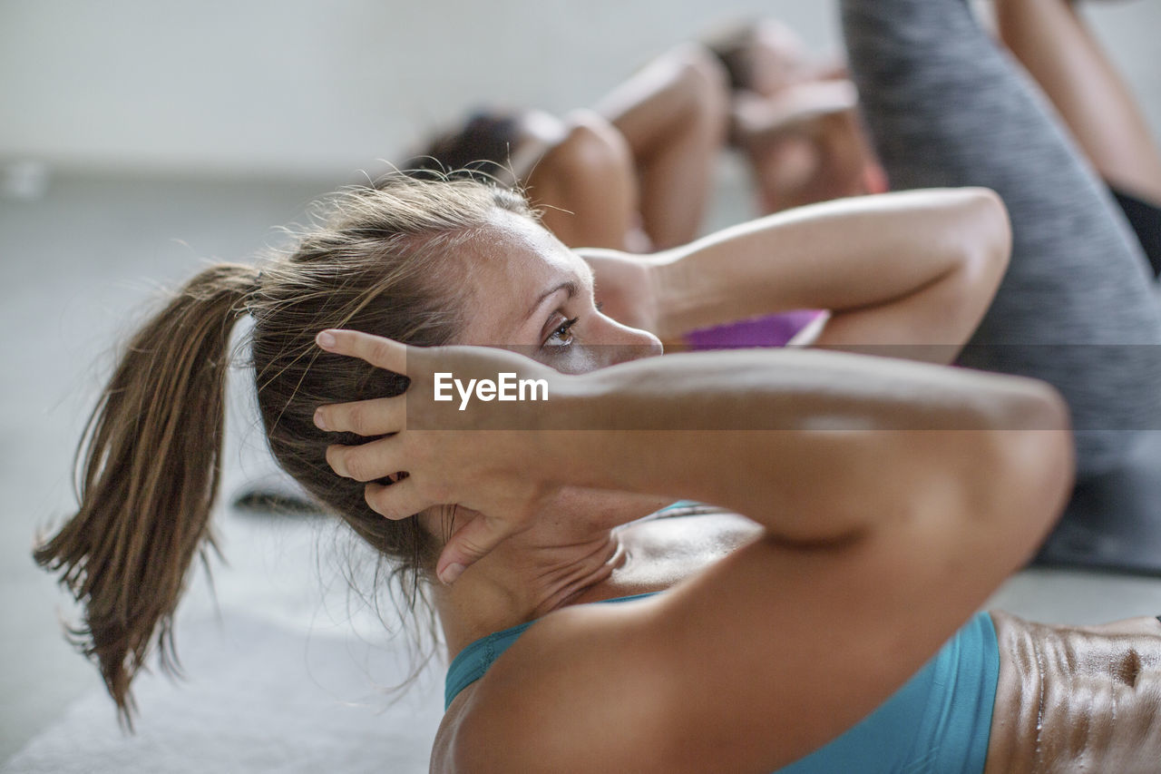 Female athletes with hands behind head exercising in gym