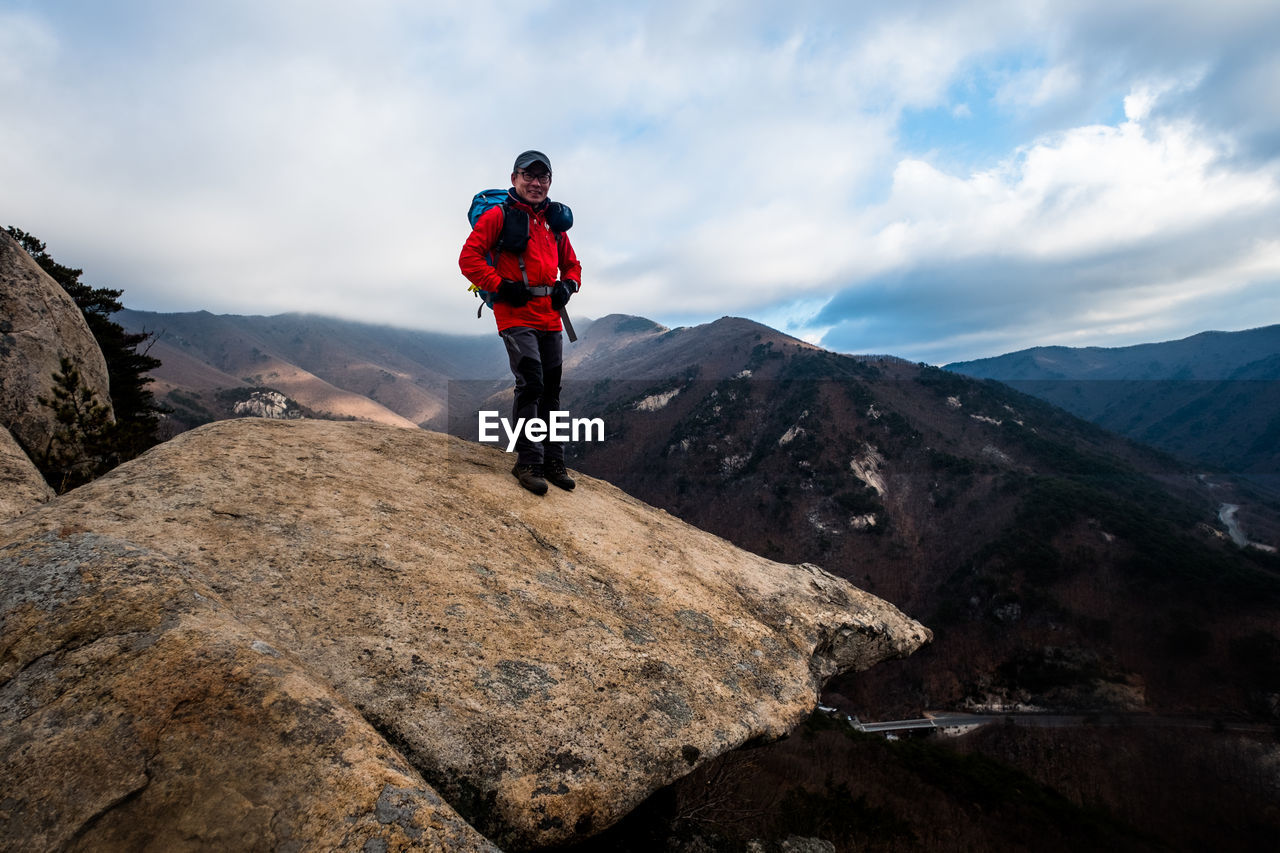 Man standing on rock against sky