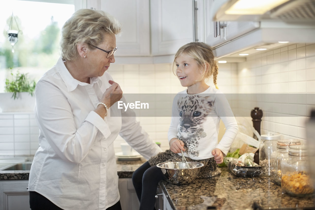 Grandmother and granddaughter preparing food in kitchen