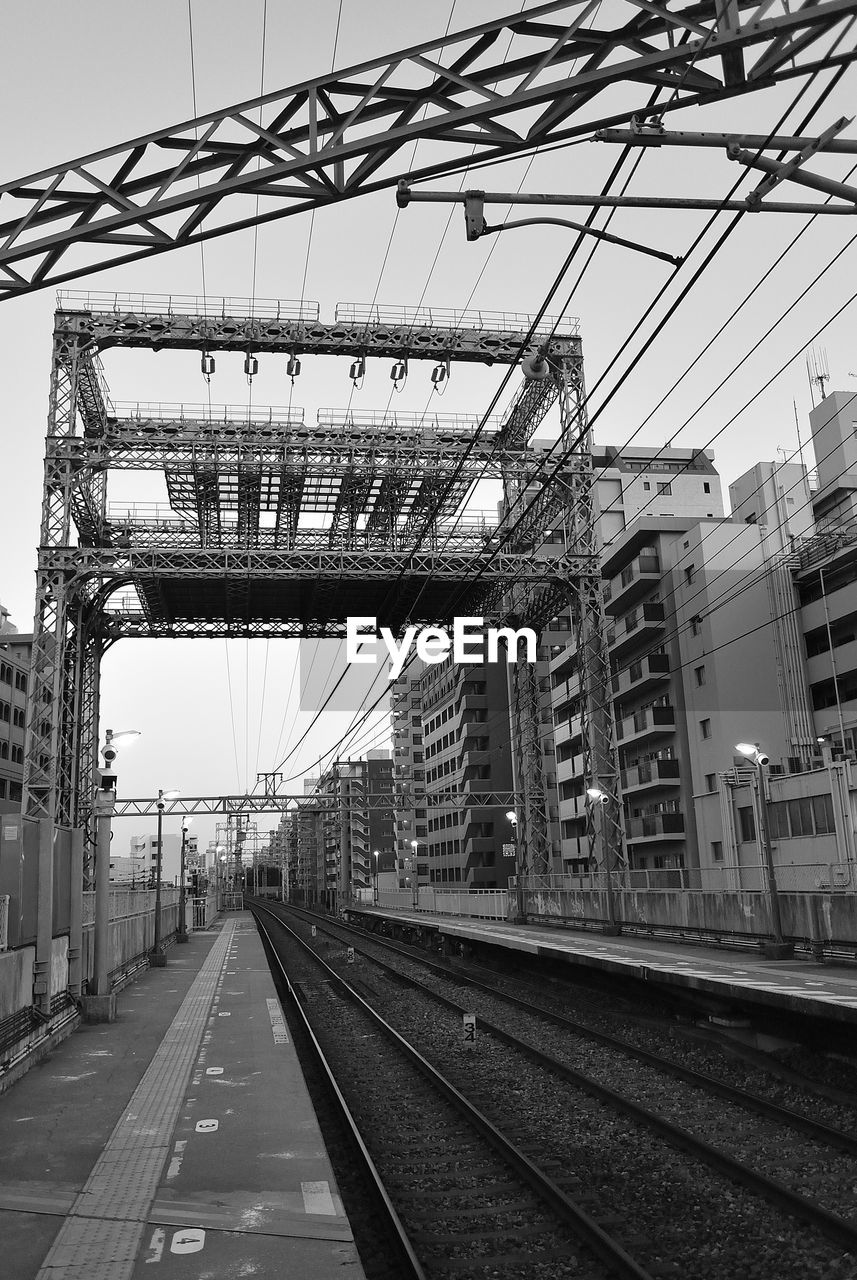 VIEW OF RAILROAD TRACKS WITH BRIDGE IN BACKGROUND