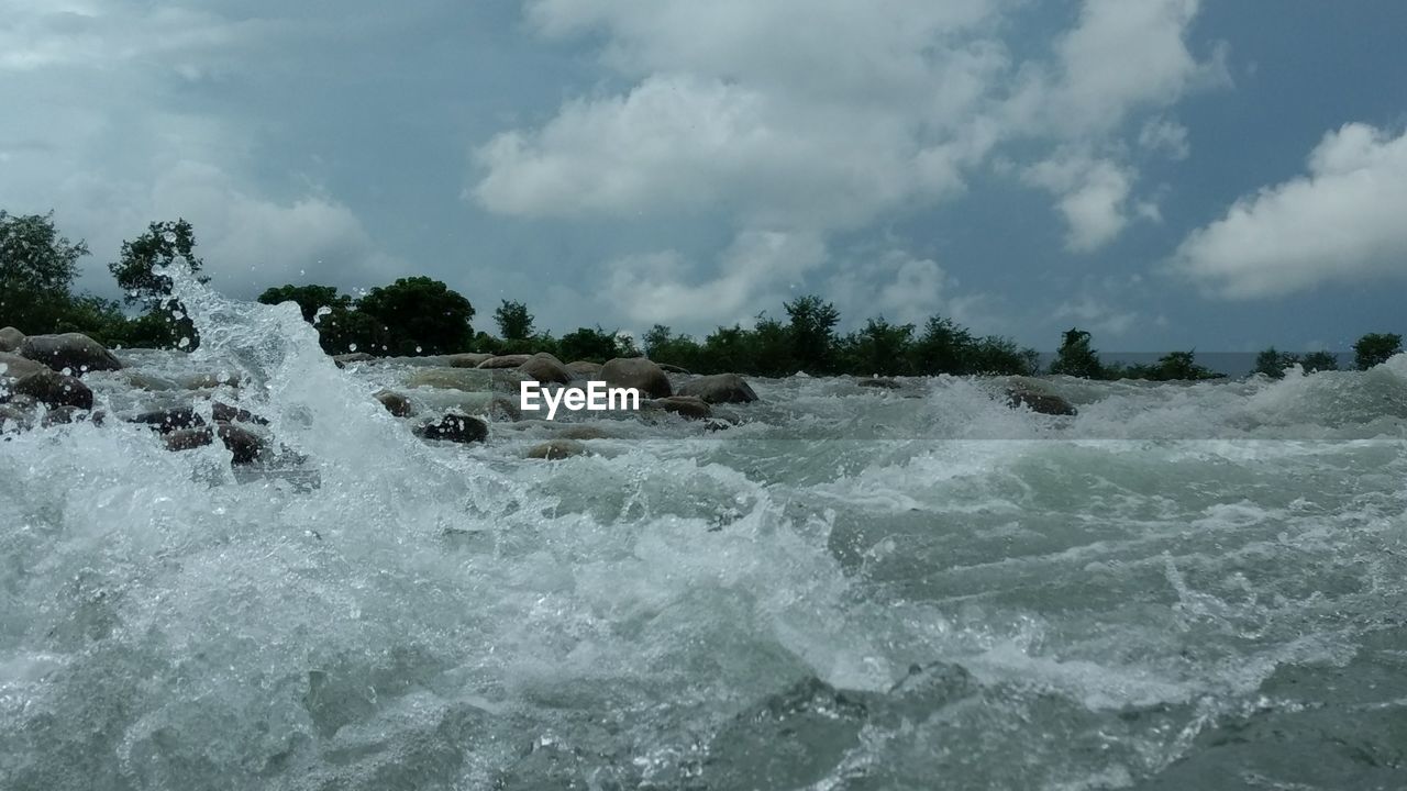 Waves splashing on shore against sky