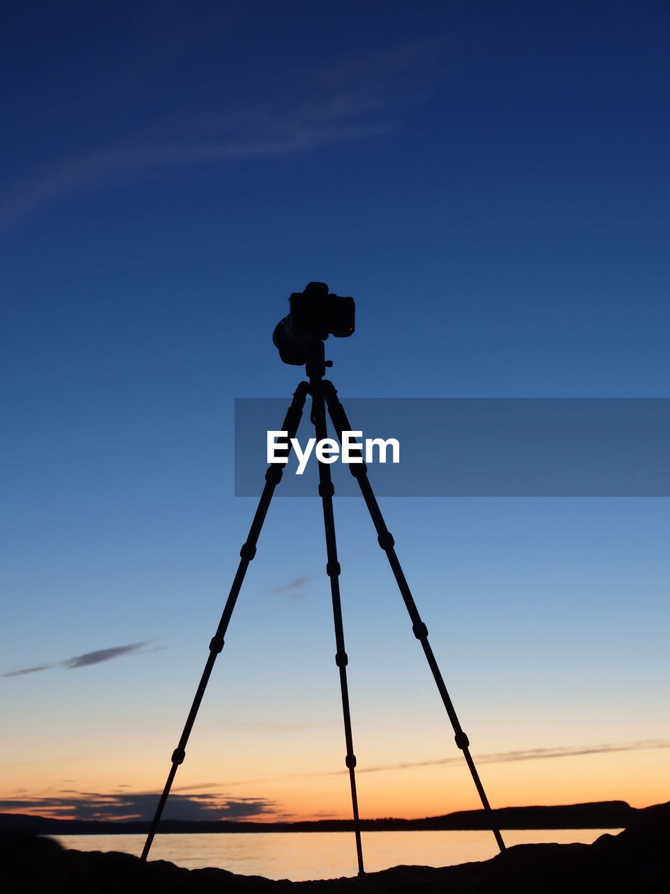 Low angle view of silhouette tripod and camera against sky during sunset