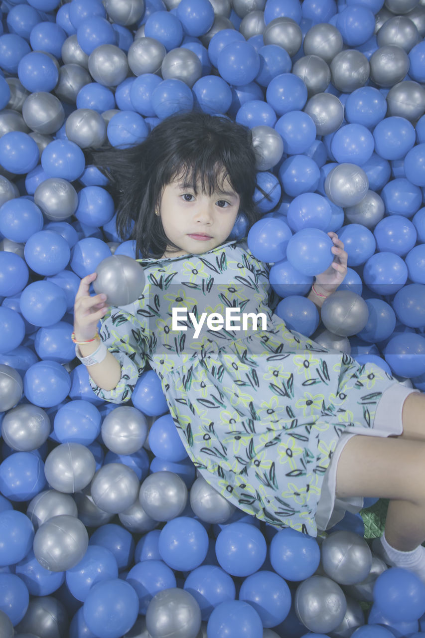 Portrait of innocent girl lying down in ball pool