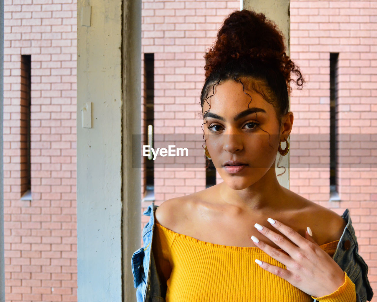 Portrait of young woman standing against wall