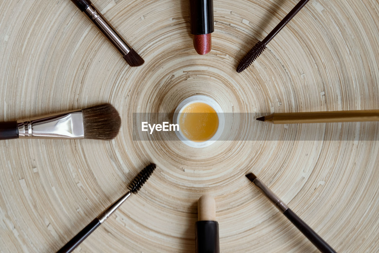 Natural vegan makeup on a wooden background - mascara, brushes, lipstick, gloss, pencil.