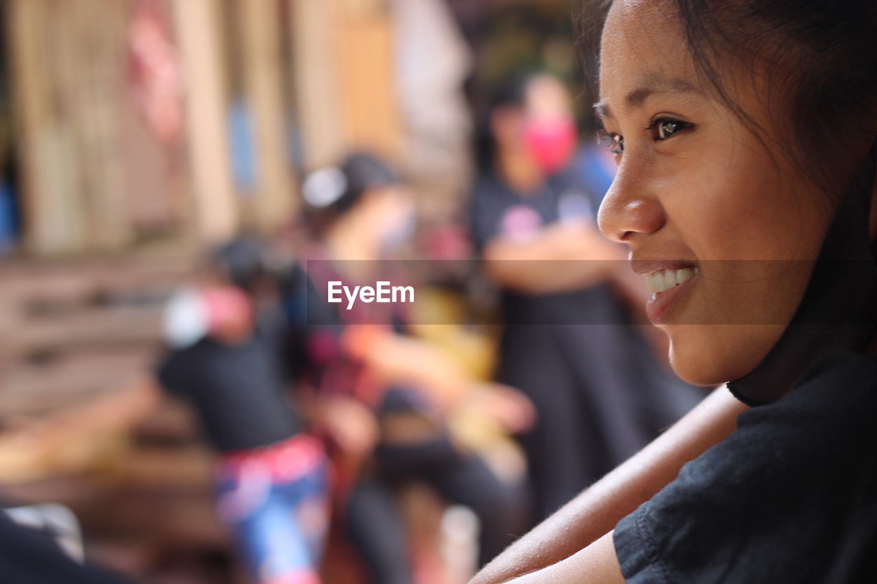 Close-up portrait of smiling young woman looking away outdoors