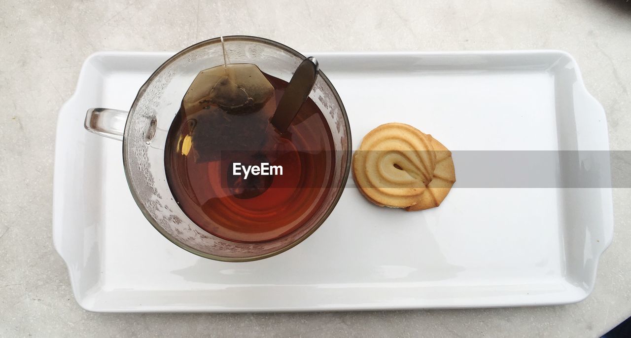 Directly above shot of black tea with cookie in tray on table