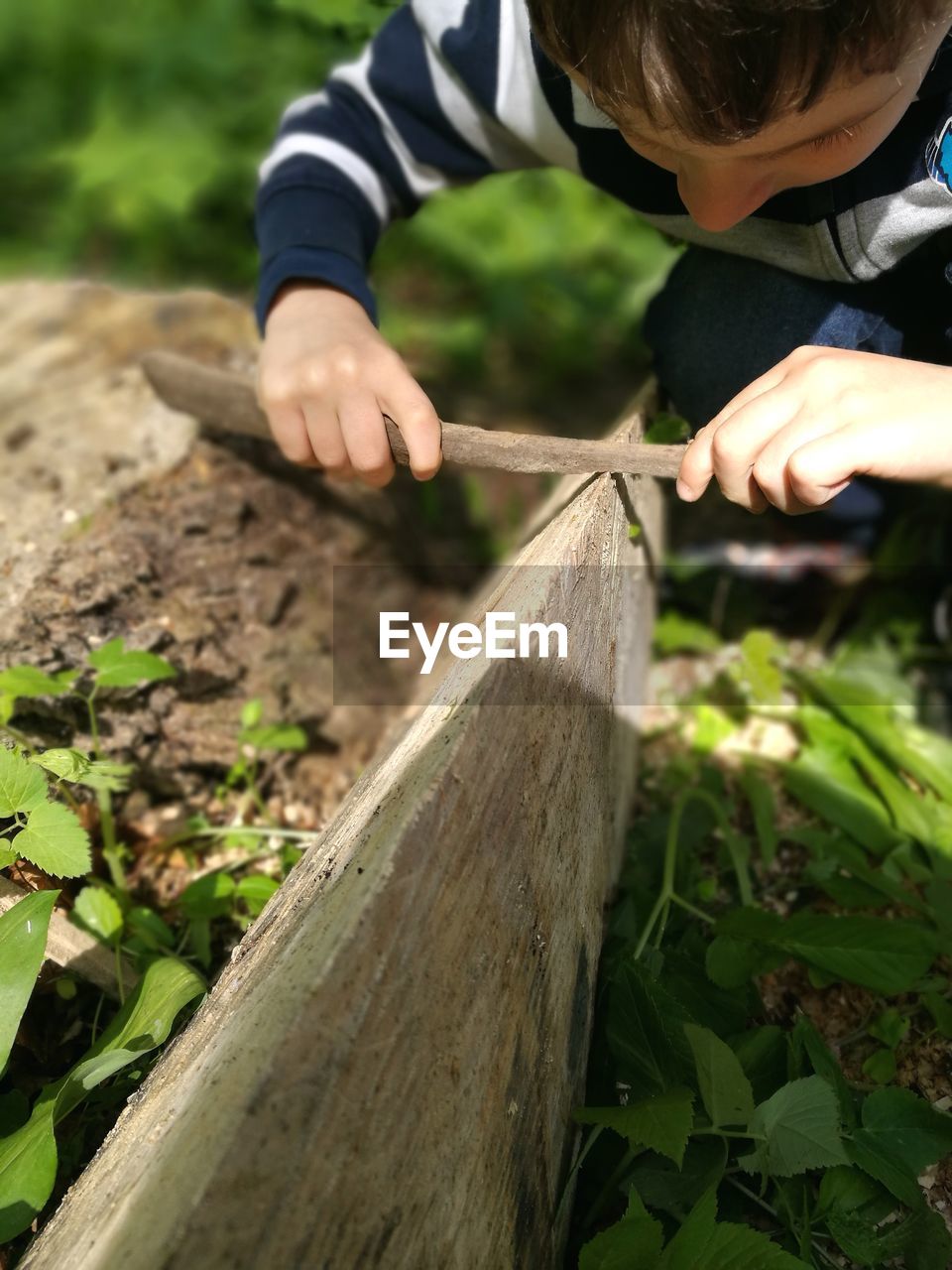 Close-up of boy rubbing stick on wood