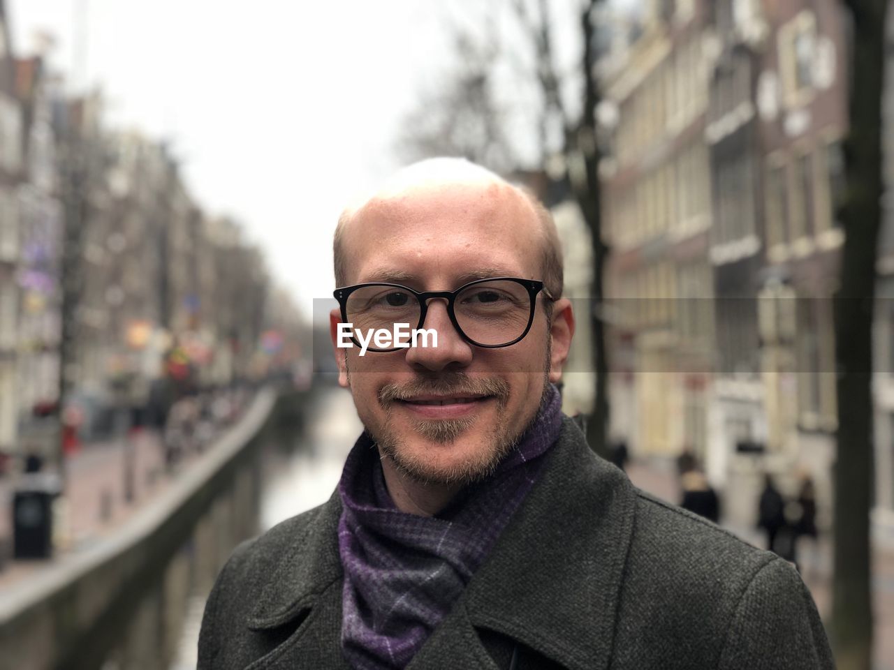 Portrait of smiling bald man standing in city