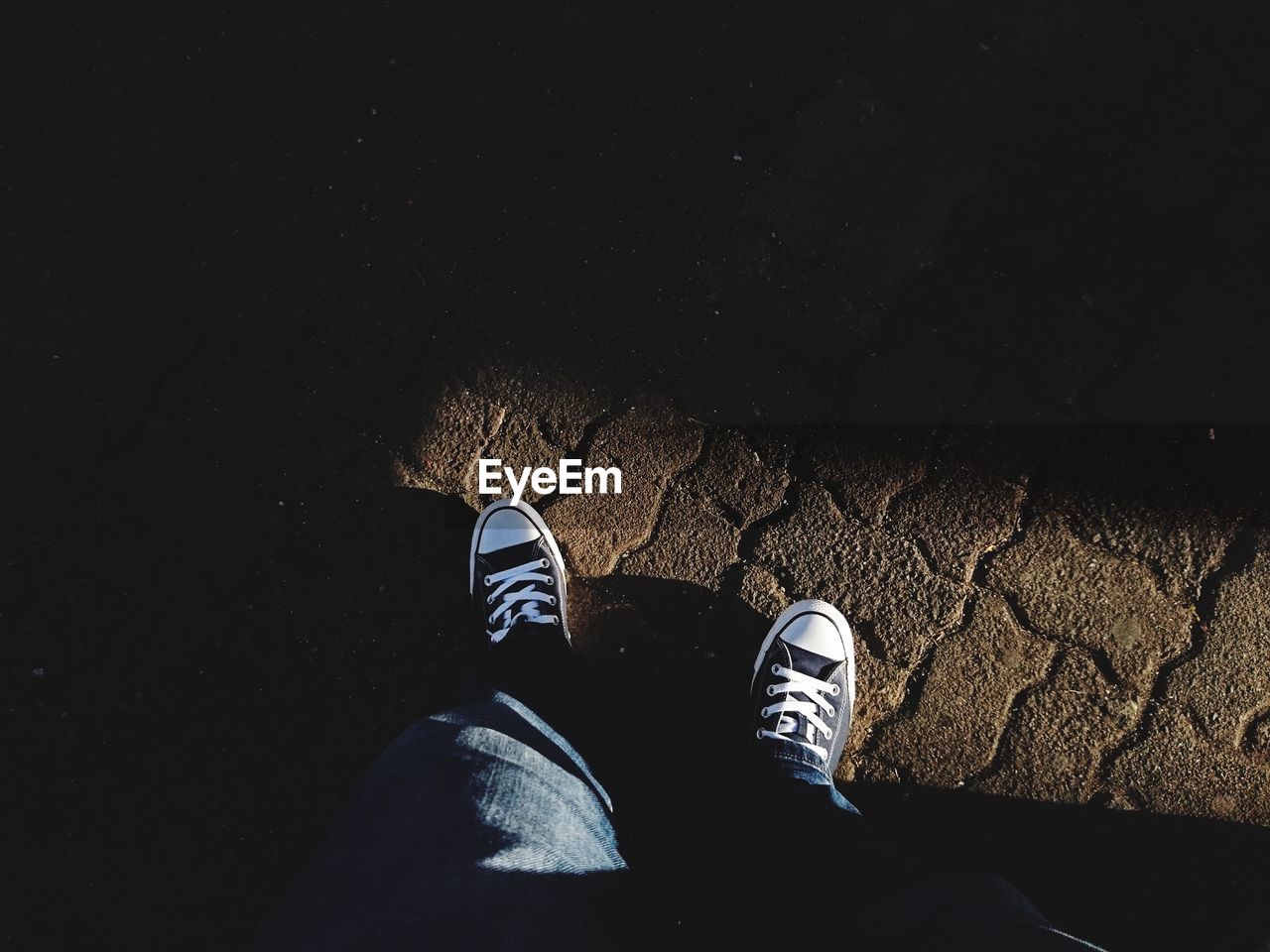 Low section of man with canvas shoes standing on footpath