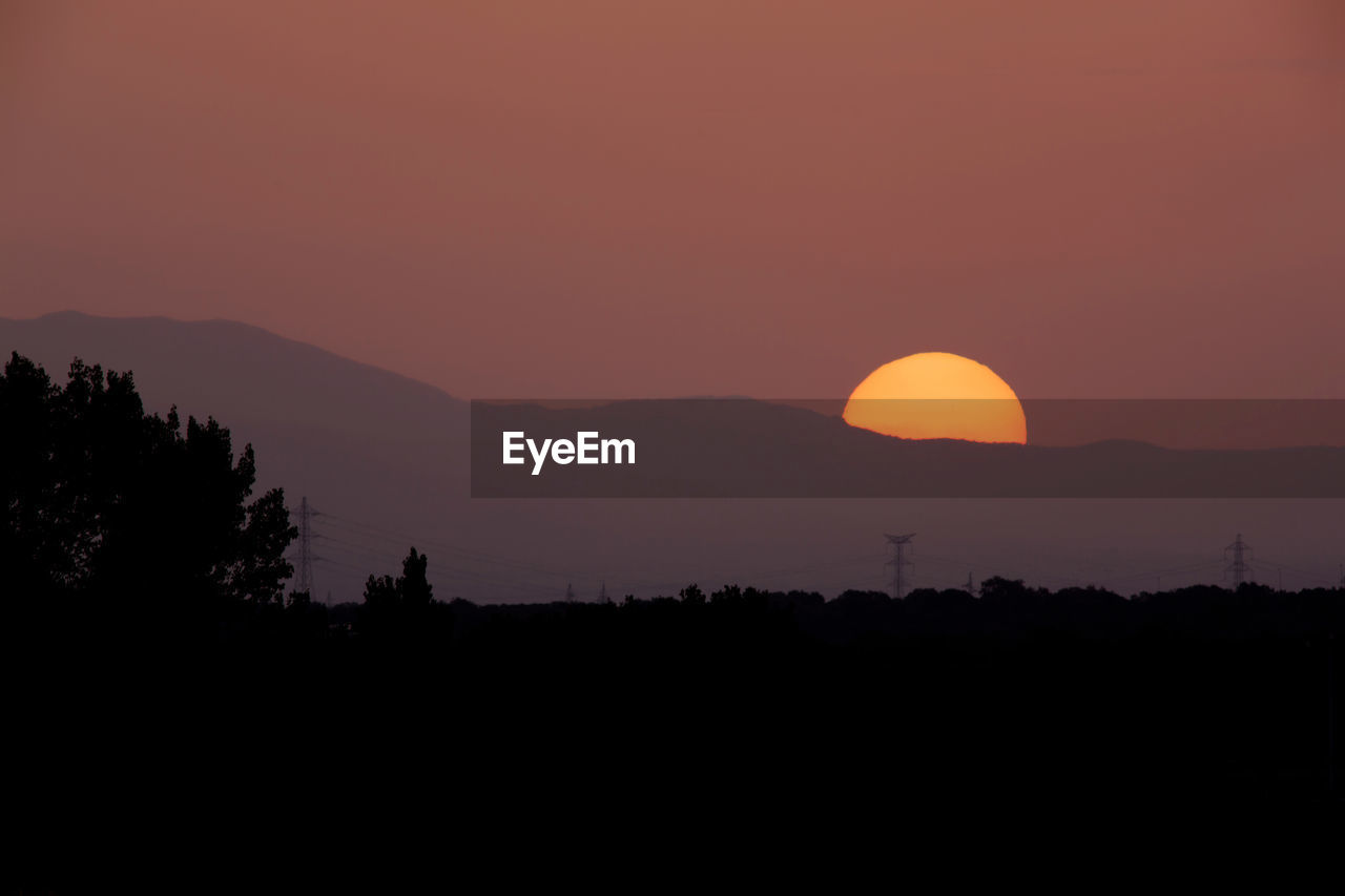 SCENIC VIEW OF SILHOUETTE MOUNTAIN AGAINST ROMANTIC SKY AT SUNSET