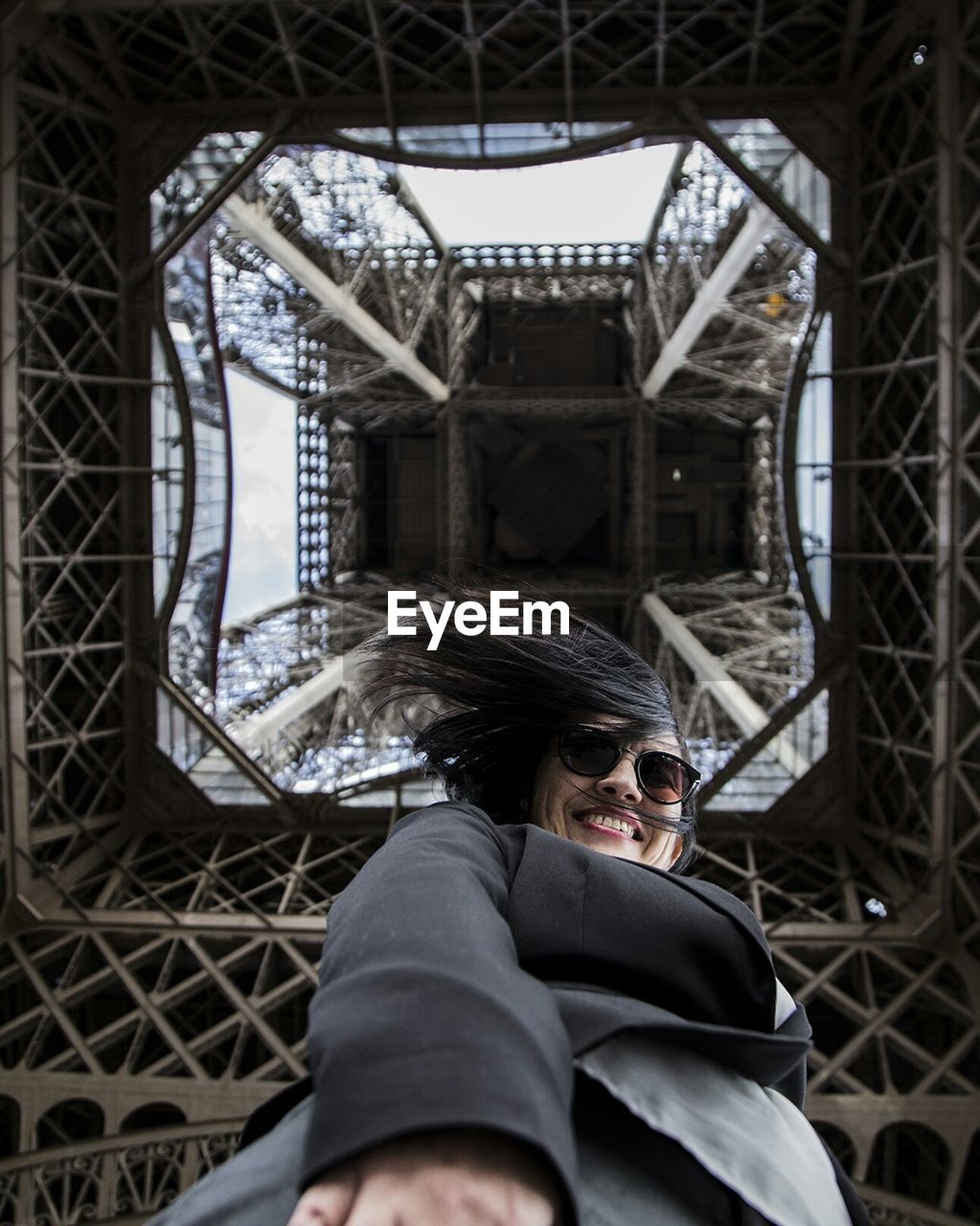Directly below shot of woman standing under eiffel tower