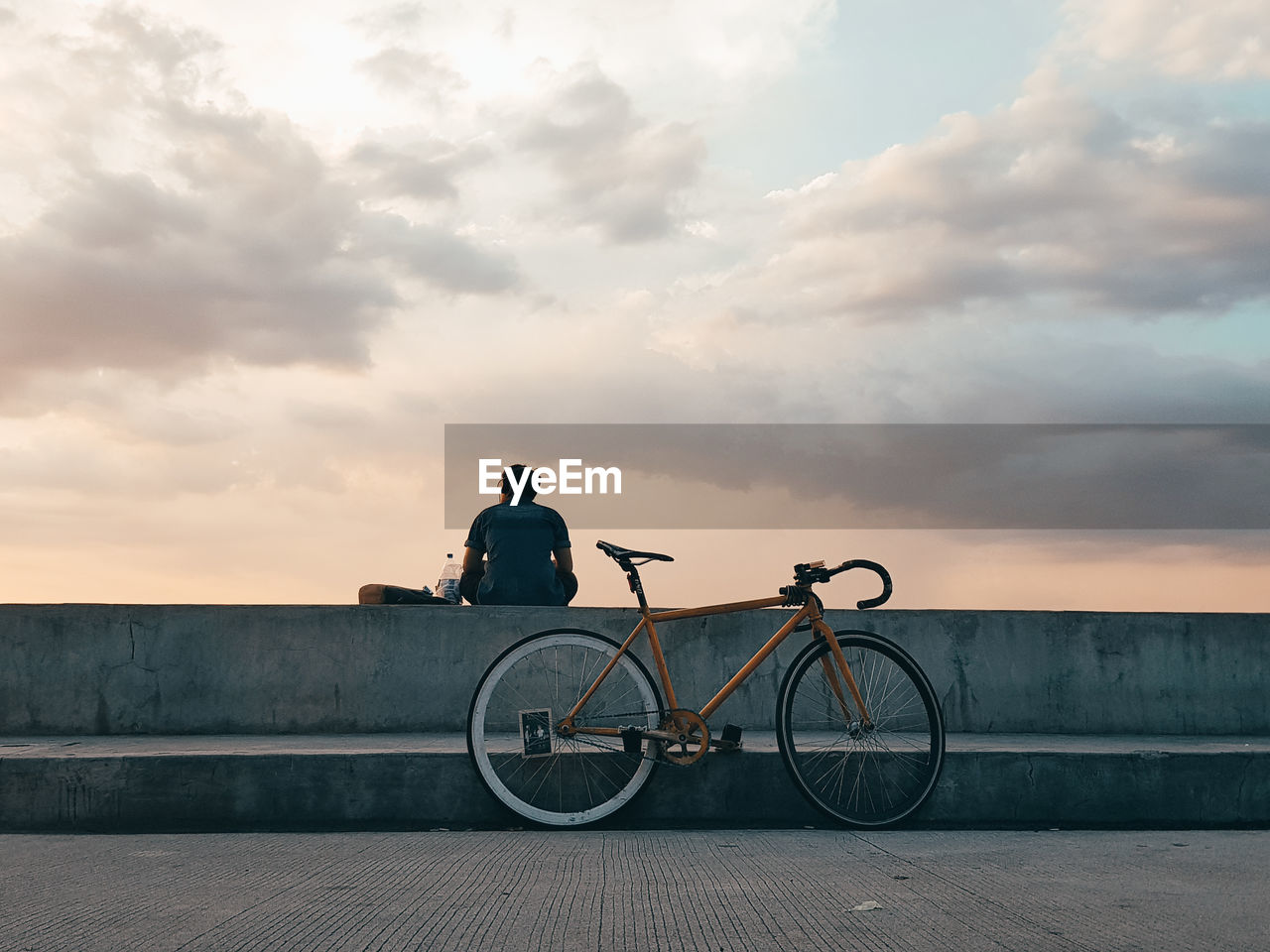 REAR VIEW OF MAN RIDING BICYCLE ON STREET