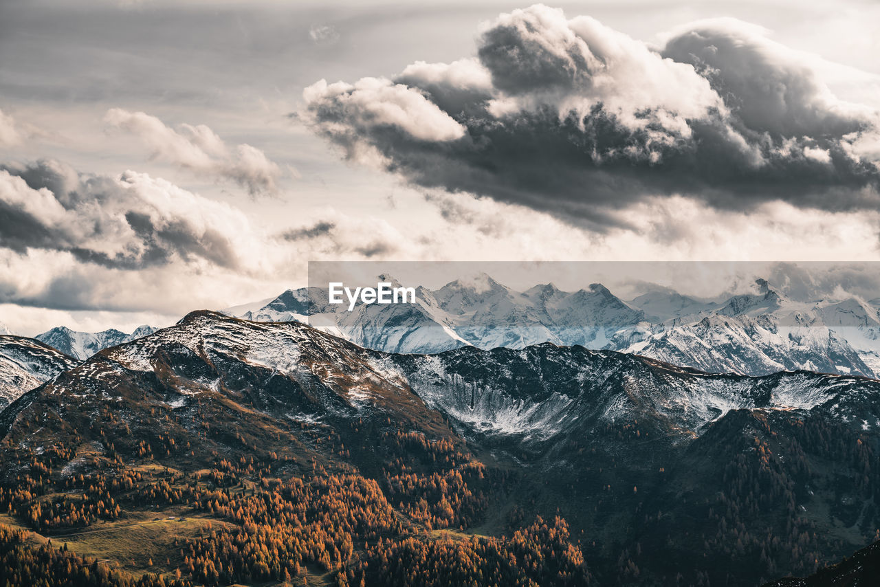 Dramatic sky over snow capped mountains in fall colors, saalbach, salzburg, austria.