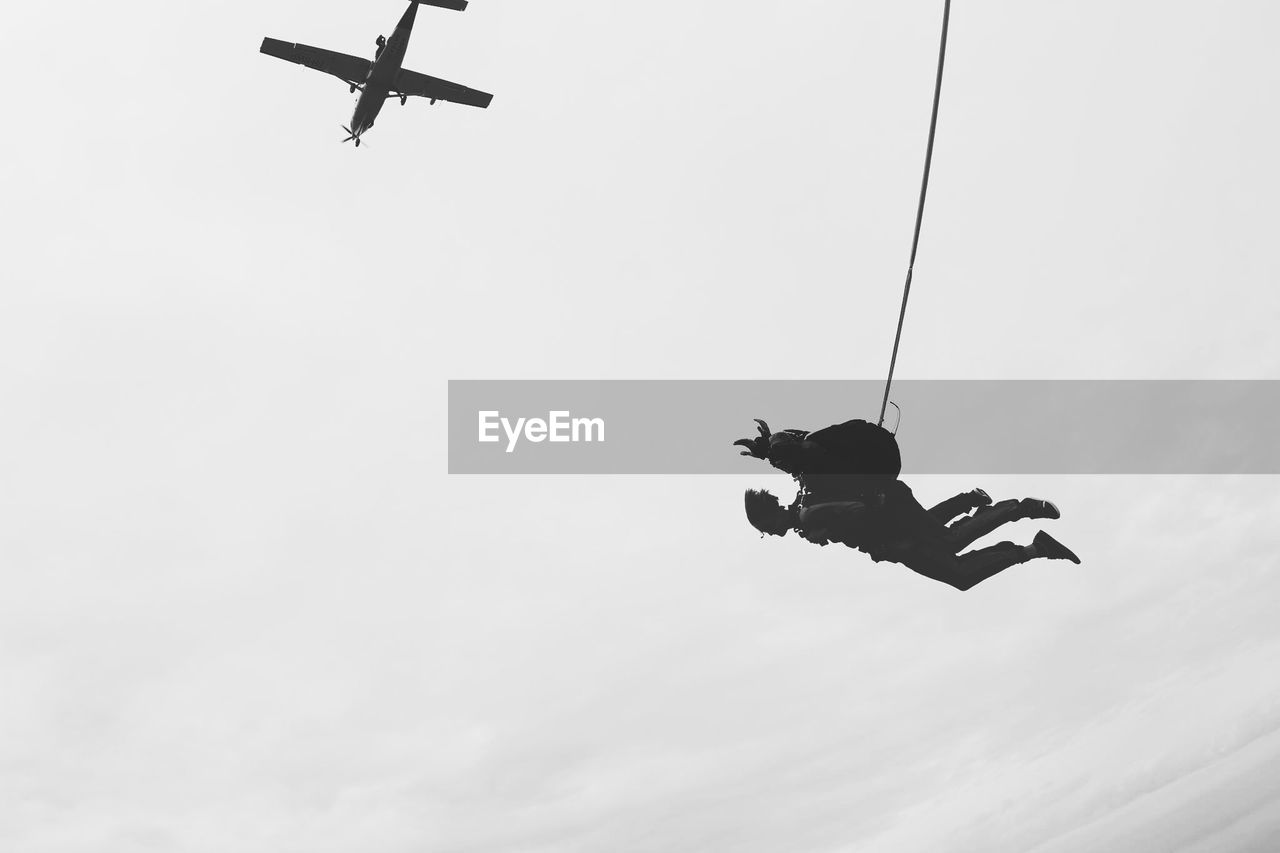 Low angle view of paragliders in mid-air against sky