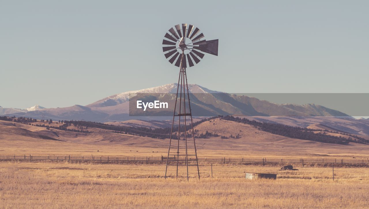 WINDMILLS ON FIELD AGAINST SKY