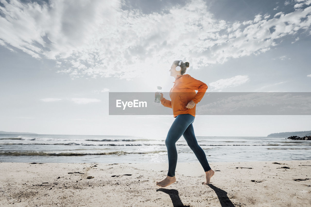 Woman jogging at beach on sunny day