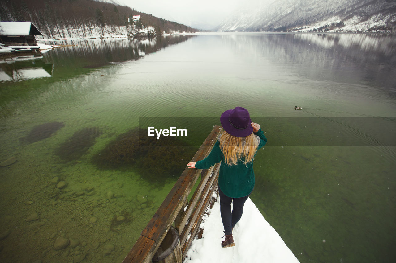 Rear view of woman on pier in lake during winter