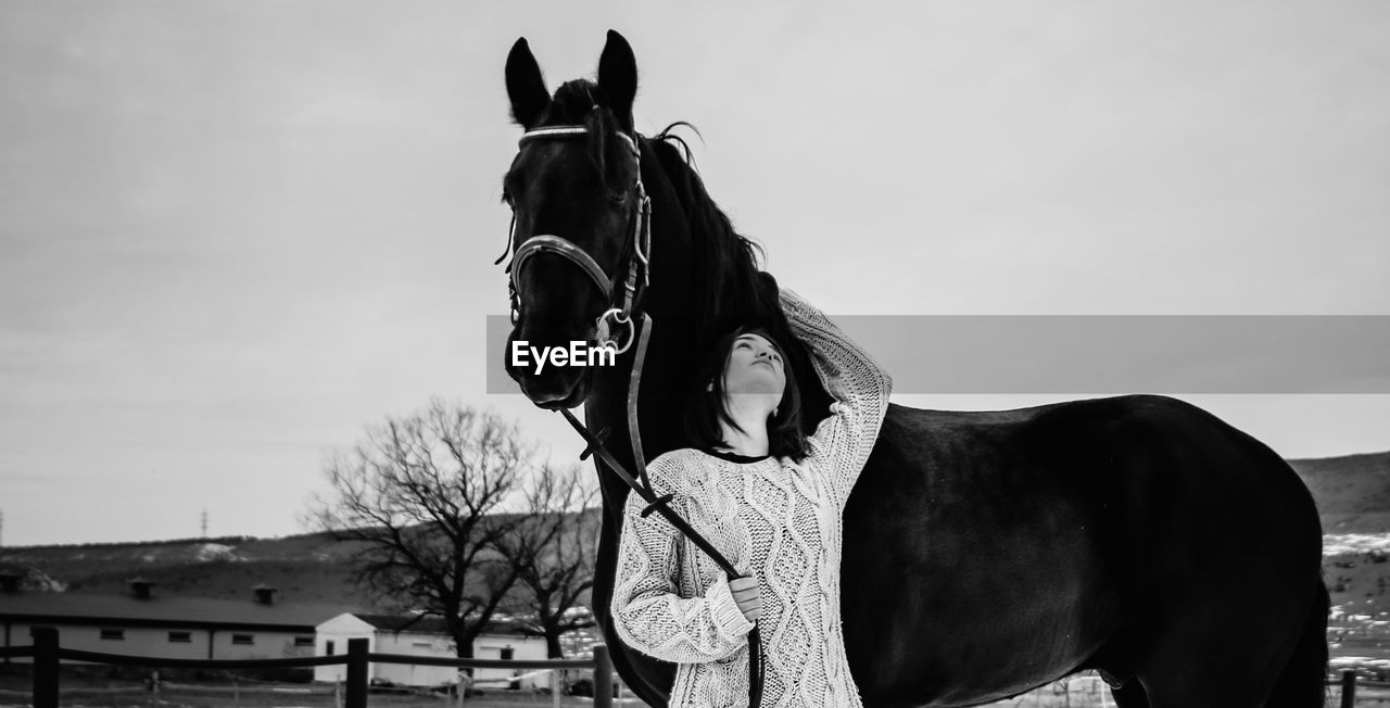 Woman standing with horse during winter