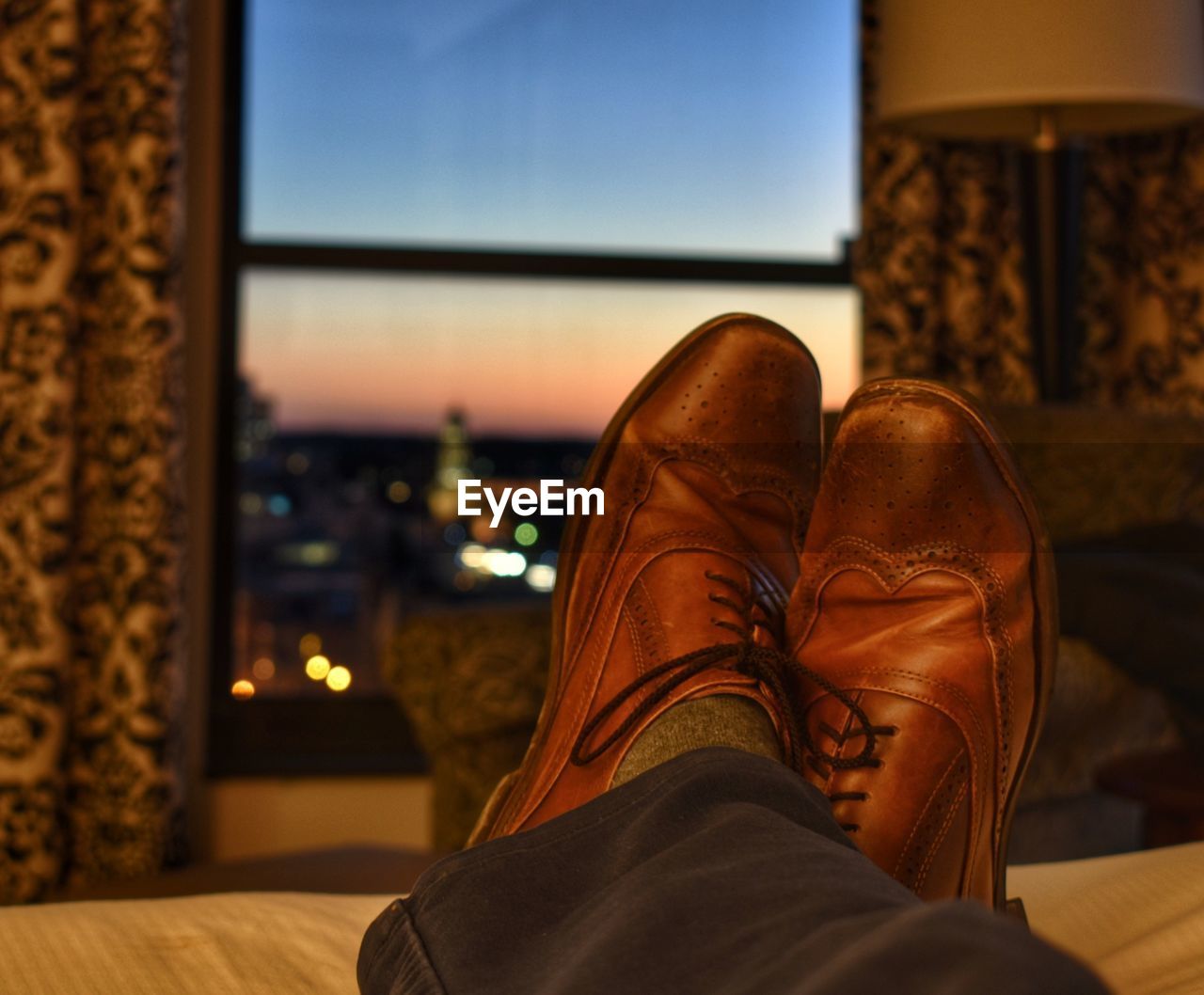 Low section of man wearing shoes sitting on bed at home