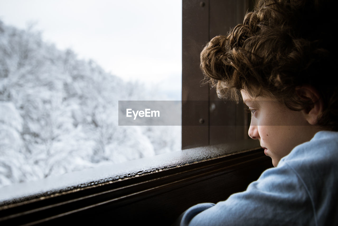 Close-up of boy looking through window