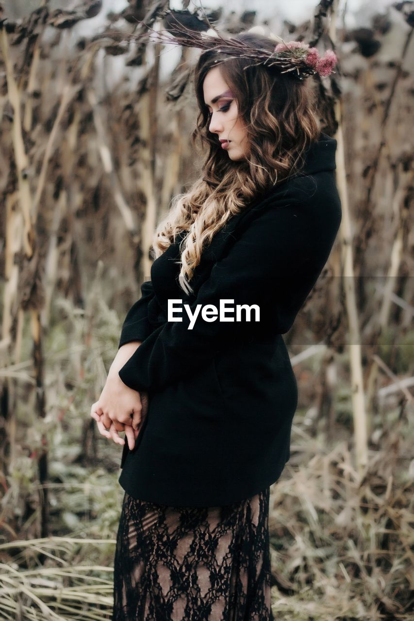 Side view of beautiful woman wearing flowers on field