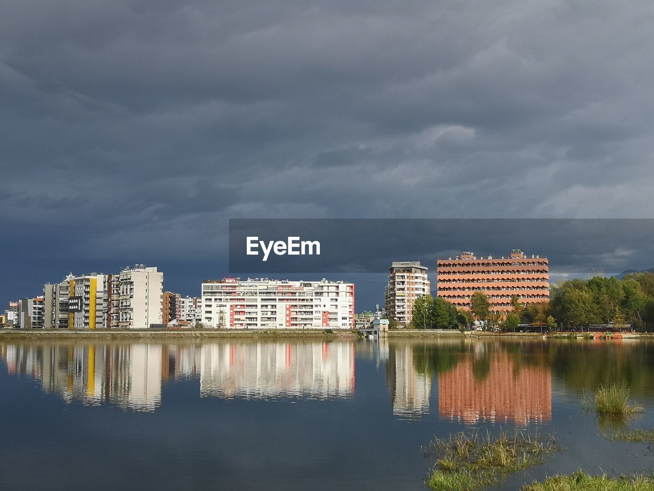 Buildings by lake against sky in city