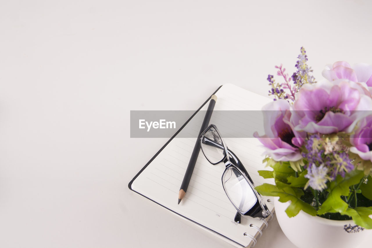 High angle view of flower in vase and book and eye glasses on table