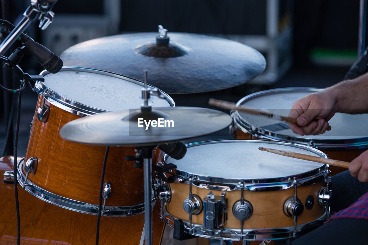 Cropped hands playing drum at night