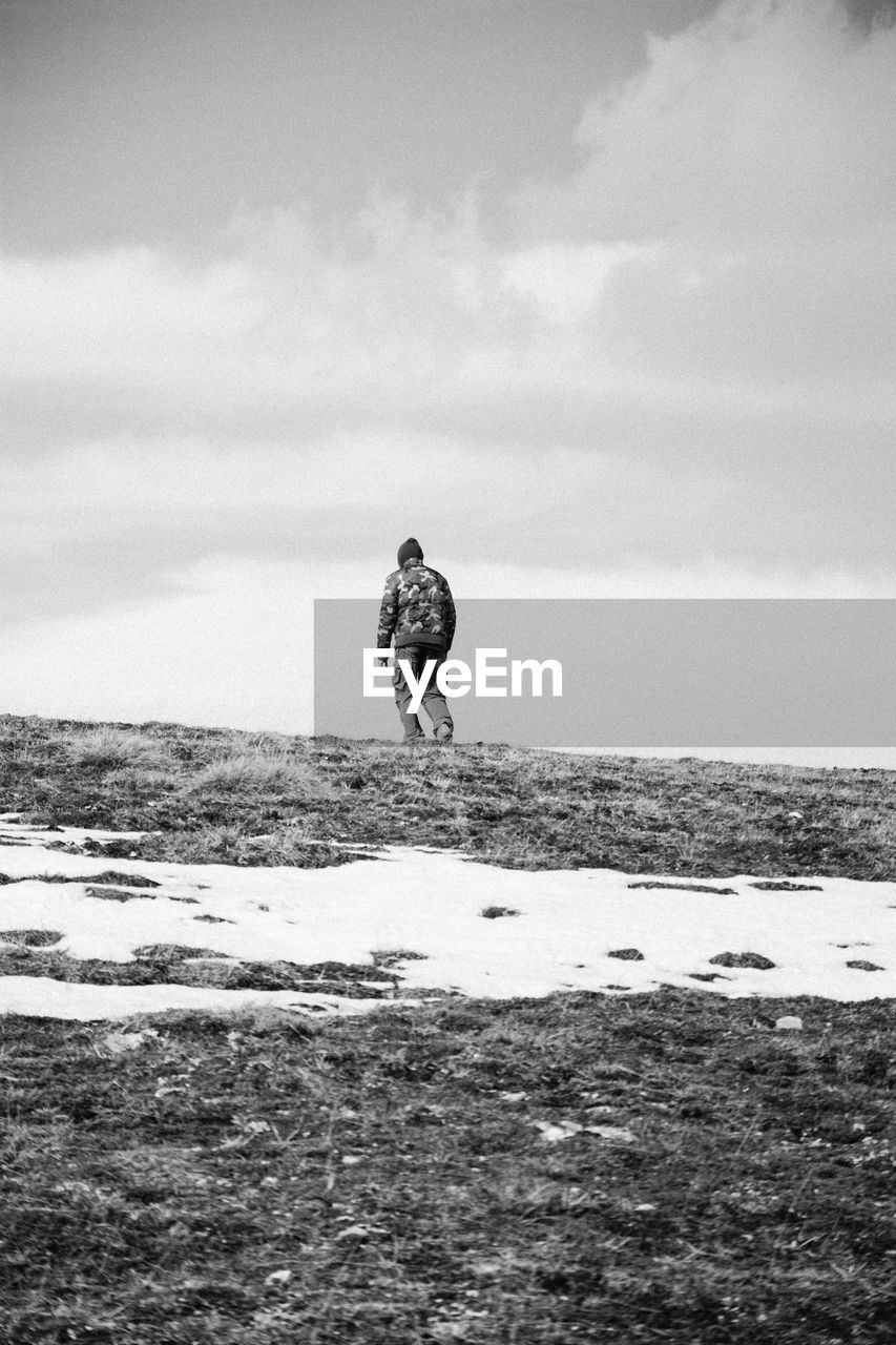 Scenic view of person on snow covered field against cloudy sky