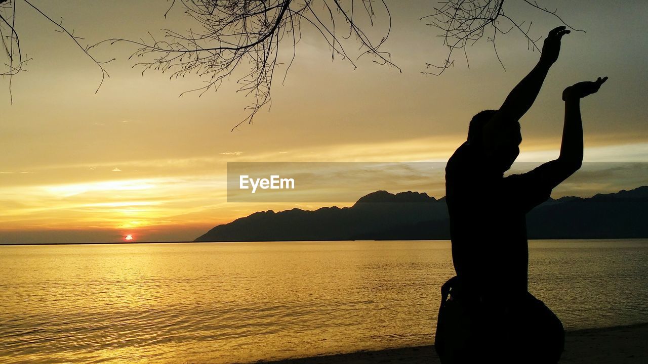 Silhouette woman by sea against sky during sunset